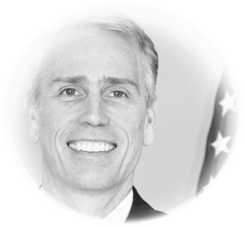 Black and white portrait with an American flag in the background.